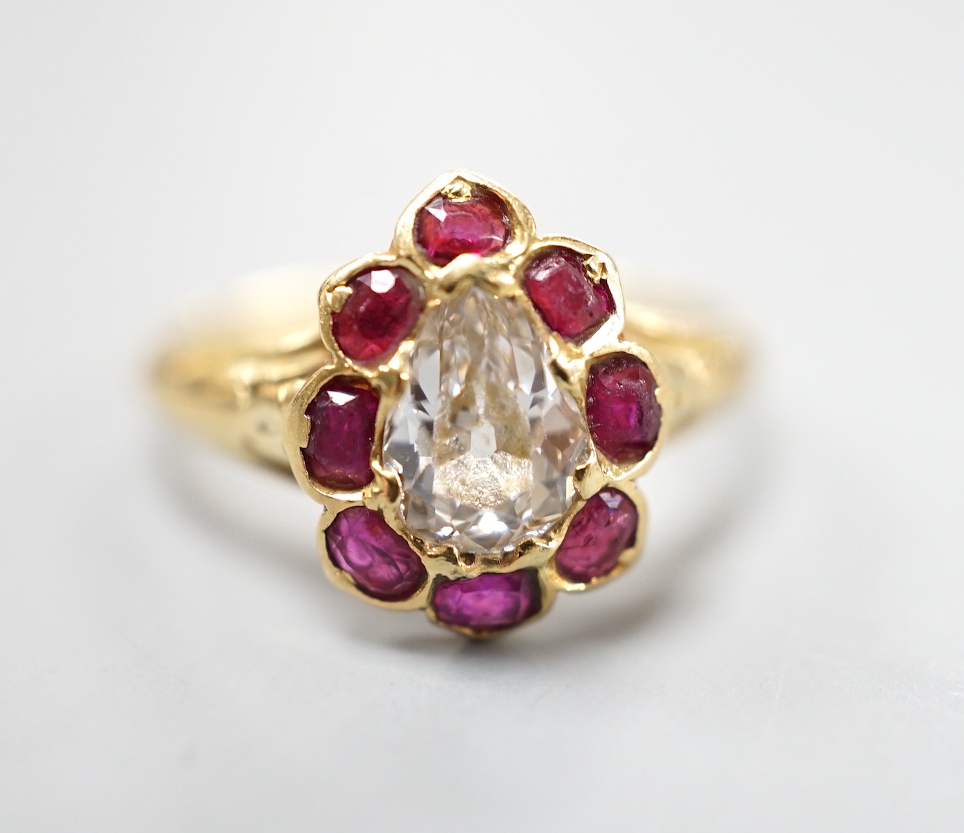 An early 20th century yellow metal and pear cut single stone diamond ring, with ruby set border, size O, gross weight 3.3 grams.